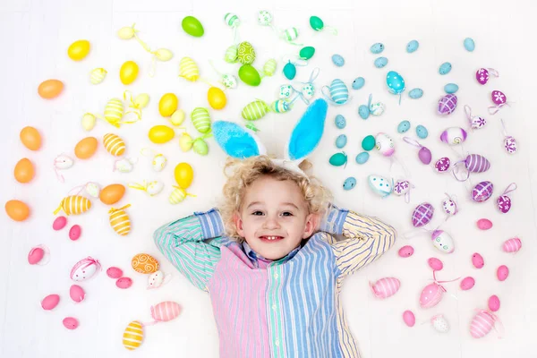 Niño en la búsqueda de huevos de Pascua. Huevos arcoiris pasteles . — Foto de Stock