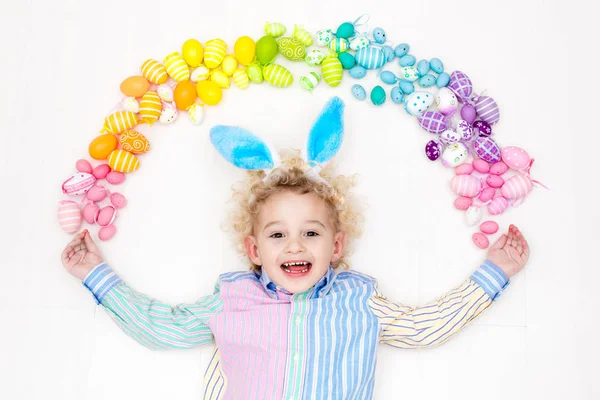 Niño en la búsqueda de huevos de Pascua. Huevos arcoiris pasteles . — Foto de Stock