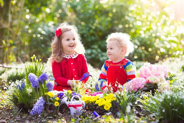 Kinderen planten en water bloemen in lentetuin — Stockfoto