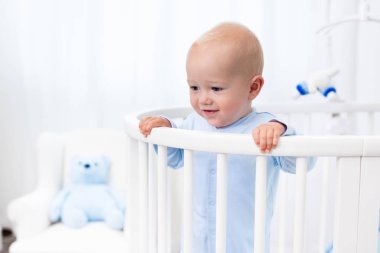 Beyaz kreş yatakta duran erkek bebek