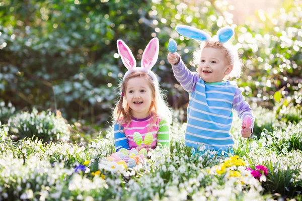 Kinderen op eieren zoeken met Pasen in de bloeiende lente tuin — Stockfoto