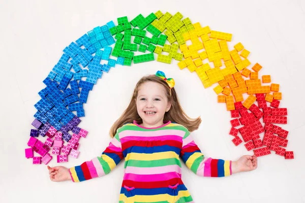 Kind spielt mit Regenbogen-Plastikklötzen — Stockfoto