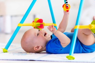 Baby boy on play mat. Child playing in gym. clipart