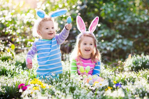 Kids on Easter egg hunt in blooming spring garden — Stock Photo, Image