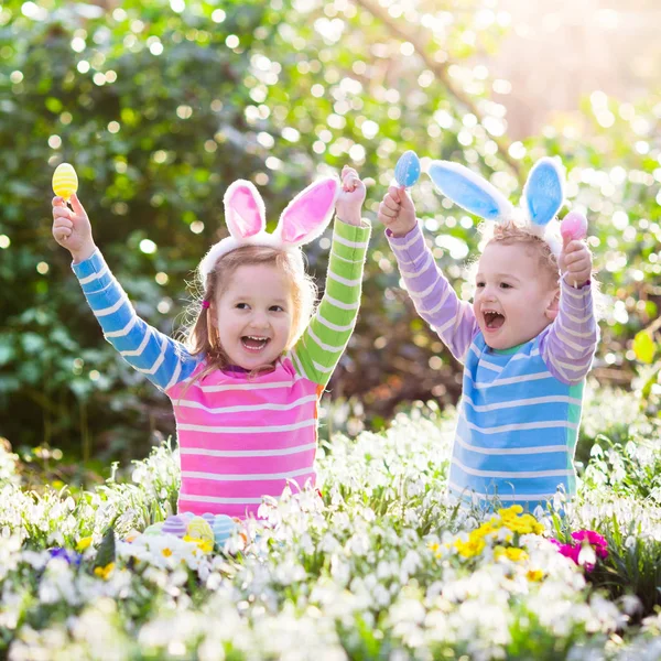 Niños en la búsqueda de huevos de Pascua en el floreciente jardín de primavera — Foto de Stock