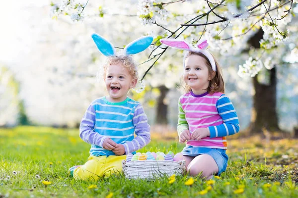 Easter egg hunt. Dzieci z bunny uszy w spring garden. — Zdjęcie stockowe