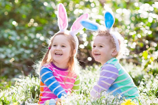 Niños en la búsqueda de huevos de Pascua en el floreciente jardín de primavera —  Fotos de Stock