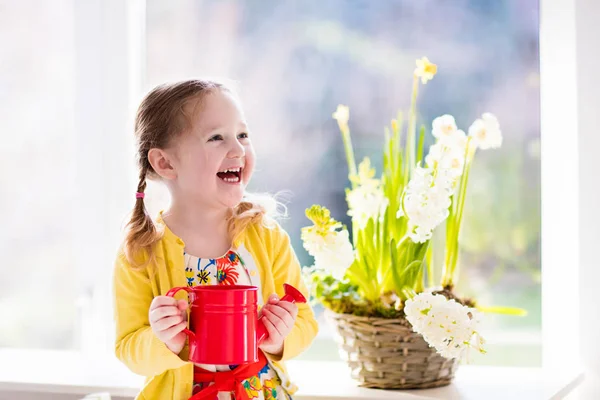 Malá dívka zalévání jarní květiny — Stock fotografie