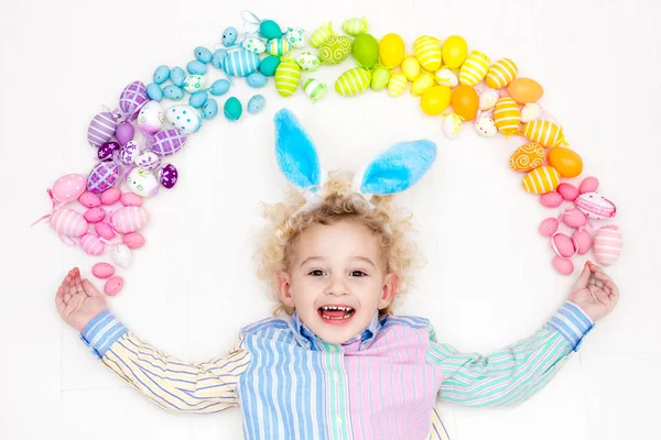 Niño en la búsqueda de huevos de Pascua. Huevos arcoiris pasteles . — Foto de Stock