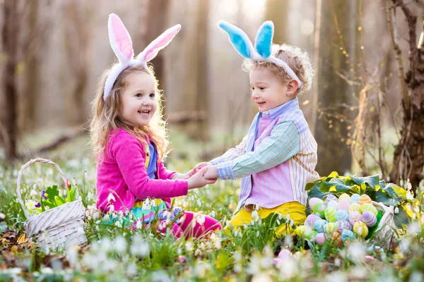 Niños en la búsqueda de huevos de Pascua en el floreciente jardín de primavera — Foto de Stock