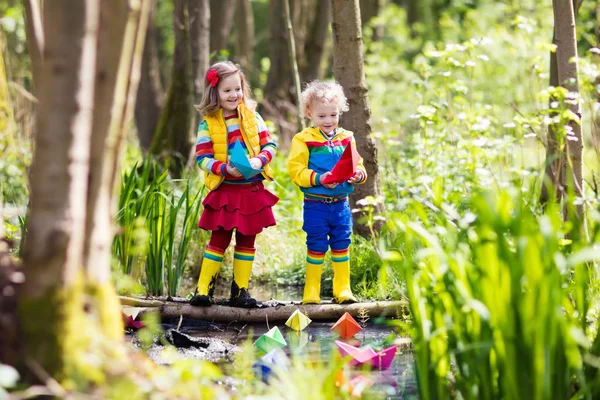 Barn som leker med färgglada papper båtar i en park — Stockfoto