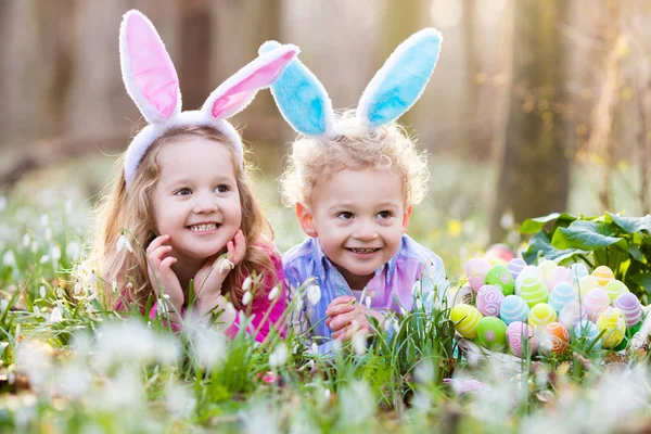 Kinderen op eieren zoeken met Pasen in de bloeiende lente tuin — Stockfoto