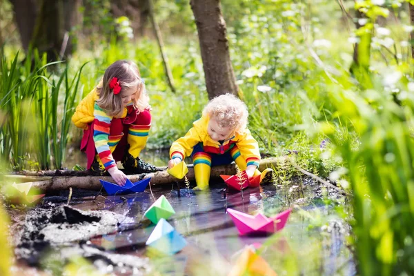 Barn som leker med färgglada papper båtar i en park — Stockfoto