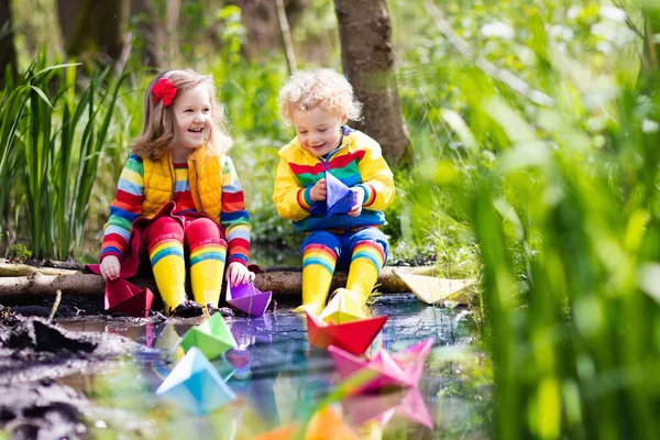 Kinder spielen mit bunten Papierbooten in einem Park — Stockfoto