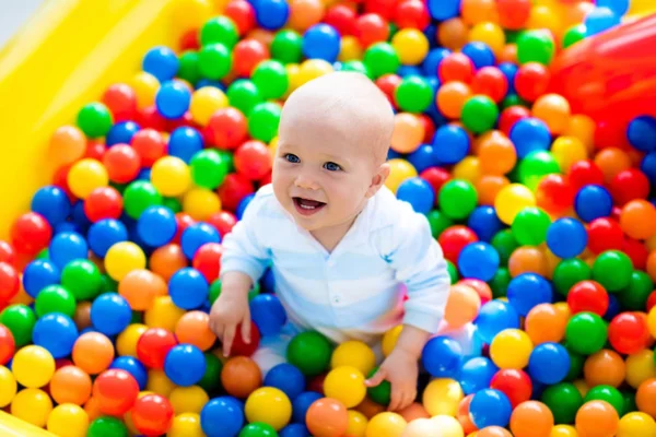 Bambino che gioca nella buca della palla nel parco giochi al coperto Immagine Stock