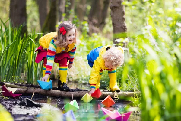 Barn som leker med färgglada papper båtar i en park — Stockfoto