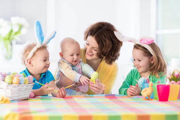 Mãe com três filhos pintando ovos de Páscoa — Fotografia de Stock