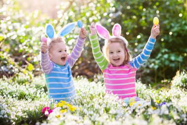 Çocuklar çiçeklenme içinde Paskalya yumurtası avına Bahçe bahar