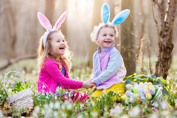 Niños en la búsqueda de huevos de Pascua en el floreciente jardín de primavera — Foto de Stock