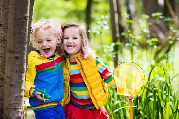 Children playing outdoors catching frog