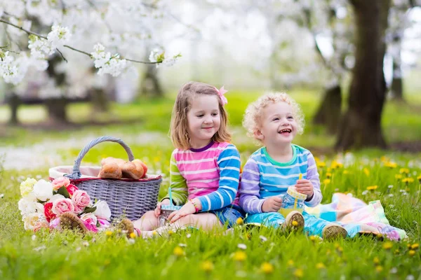 Kids having picnic in blooming garden — Stock Photo, Image