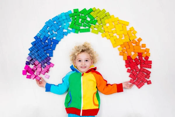 Kind spielt mit Regenbogen-Plastikklötzen — Stockfoto