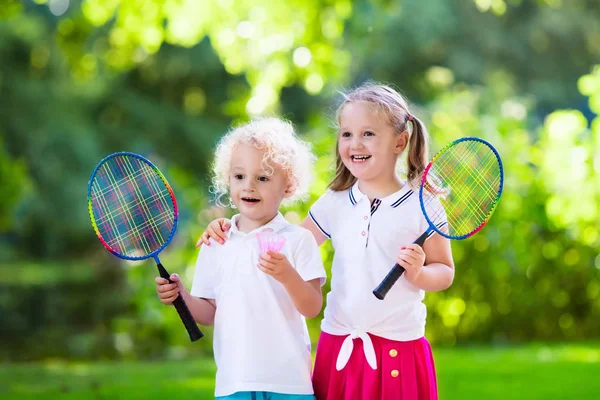 Kids play badminton or tennis in outdoor court