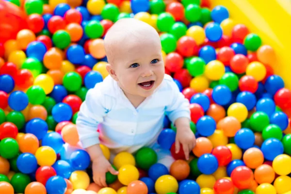 Bambino che gioca nella buca della palla nel parco giochi al coperto Foto Stock