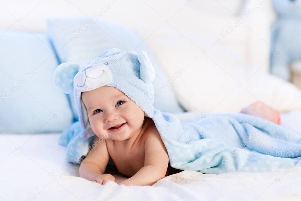 Baby in towel after bath in bed