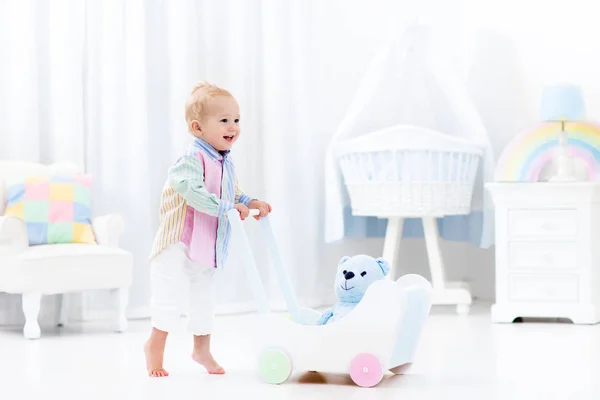 Baby with push walker in white bedroom — Stock Photo, Image