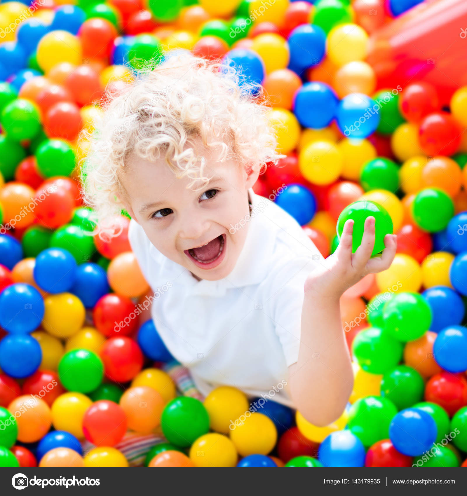 Child playing in ball pit on indoor playground Stock Photo by