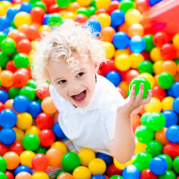 Criança brincando no poço de bolas no parque infantil interior — Fotografia de Stock