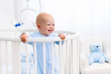 Beyaz kreş yatakta duran erkek bebek