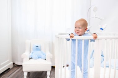 Beyaz kreş yatakta duran erkek bebek
