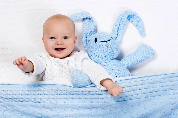 Baby boy playing with bunny toy in bed — Stock Photo, Image