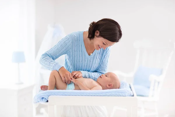 Mother changing diaper to baby boy