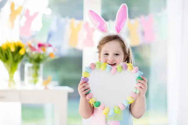 Niña en orejas de conejo en la búsqueda de huevos de Pascua — Foto de Stock