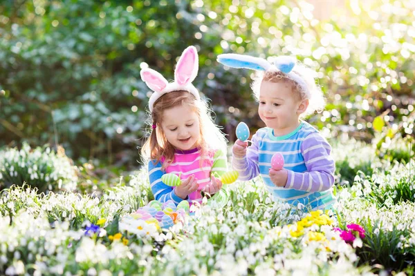 Niños en la búsqueda de huevos de Pascua en el floreciente jardín de primavera — Foto de Stock