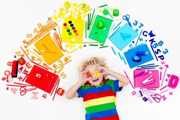 Child with school and drawing supplies. Student with book.