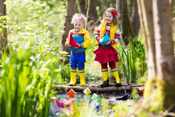 Kinder spielen mit bunten Papierbooten in einem Park — Stockfoto