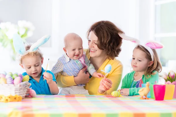 Mor med tre barn måla påskägg — Stockfoto
