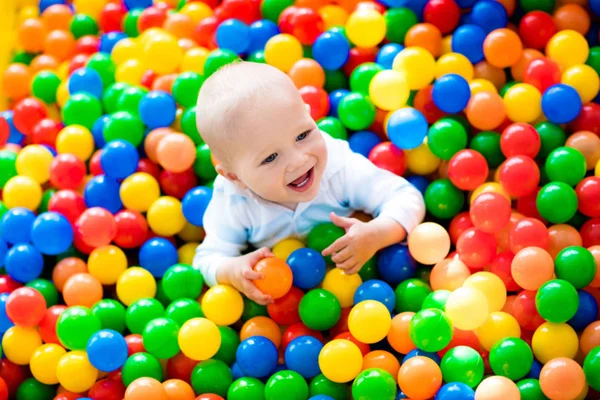 Criança brincando no poço de bolas no parque infantil interior — Fotografia de Stock