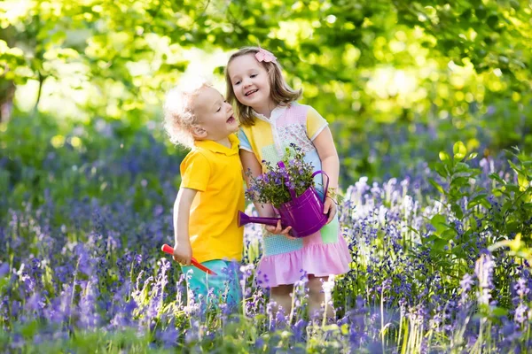 Kinderen spelen in de bloeiende tuin met bluebell bloemen — Stockfoto