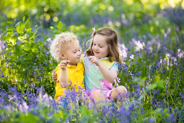 Děti hrají v kvetoucí zahradě květinami bluebell — Stock fotografie