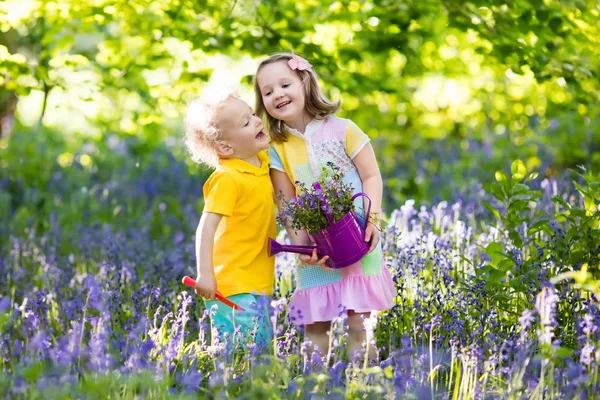 Kids playing in blooming garden with bluebell flowers Royalty Free Stock Photos
