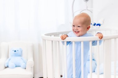 Beyaz kreş yatakta duran erkek bebek