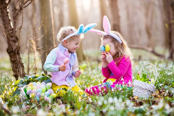 Niños en la búsqueda de huevos de Pascua en el floreciente jardín de primavera —  Fotos de Stock