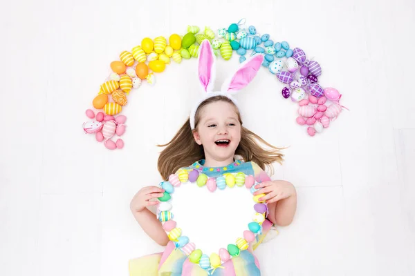Niño en la búsqueda de huevos de Pascua. Huevos arcoiris pasteles . — Foto de Stock