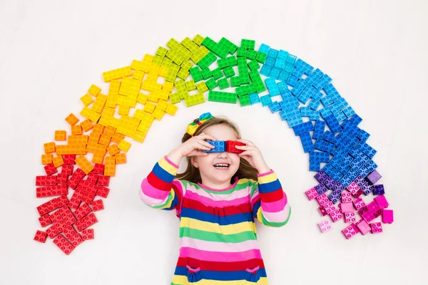 Kind spielt mit Regenbogen-Plastikklötzen — Stockfoto