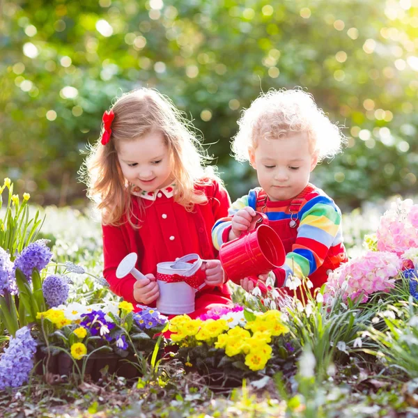 Kinder pflanzen und gießen Blumen im Frühlingsgarten — Stockfoto